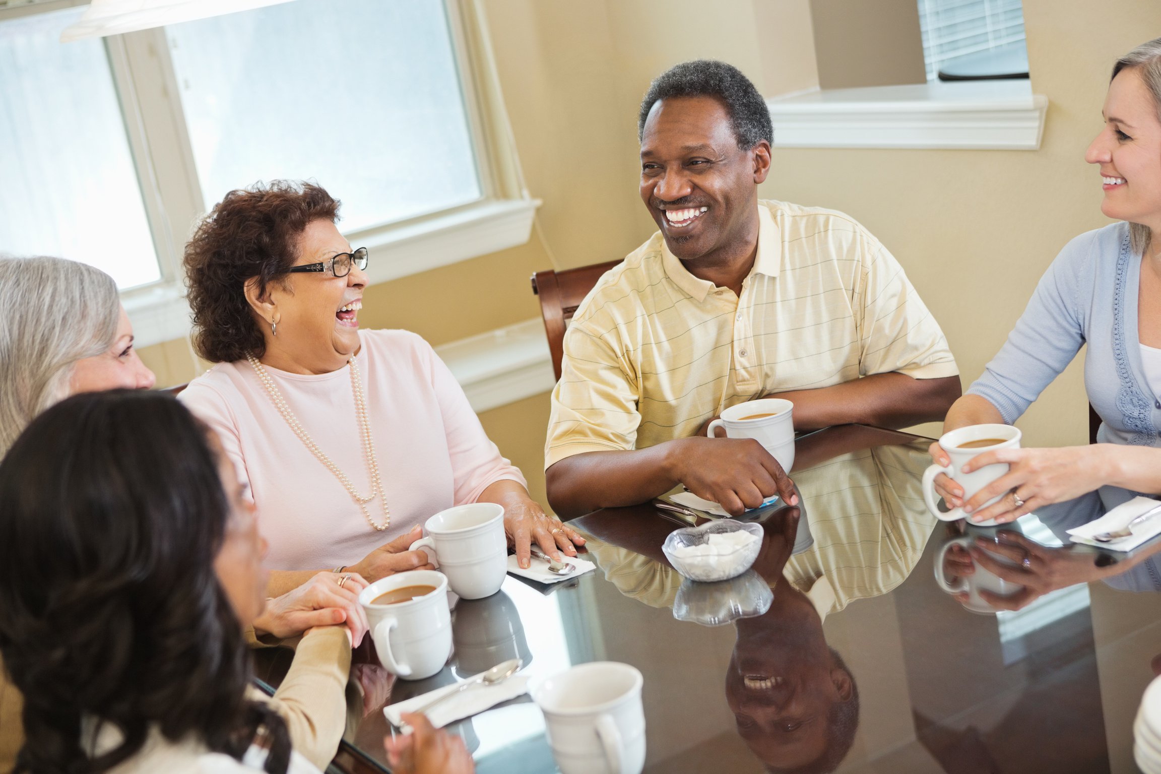 Group of diverse senior friends having coffee at home